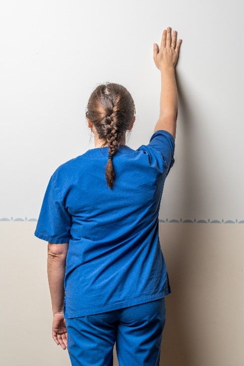 Naine liigutab opereeritud kehapoole kätt mööda seina üles ja alla.